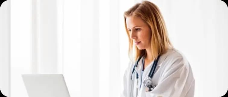 Doctor in a white coat working on a laptop