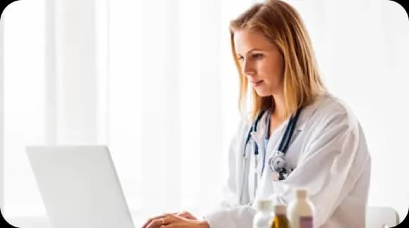 Doctor in a white coat working on a laptop